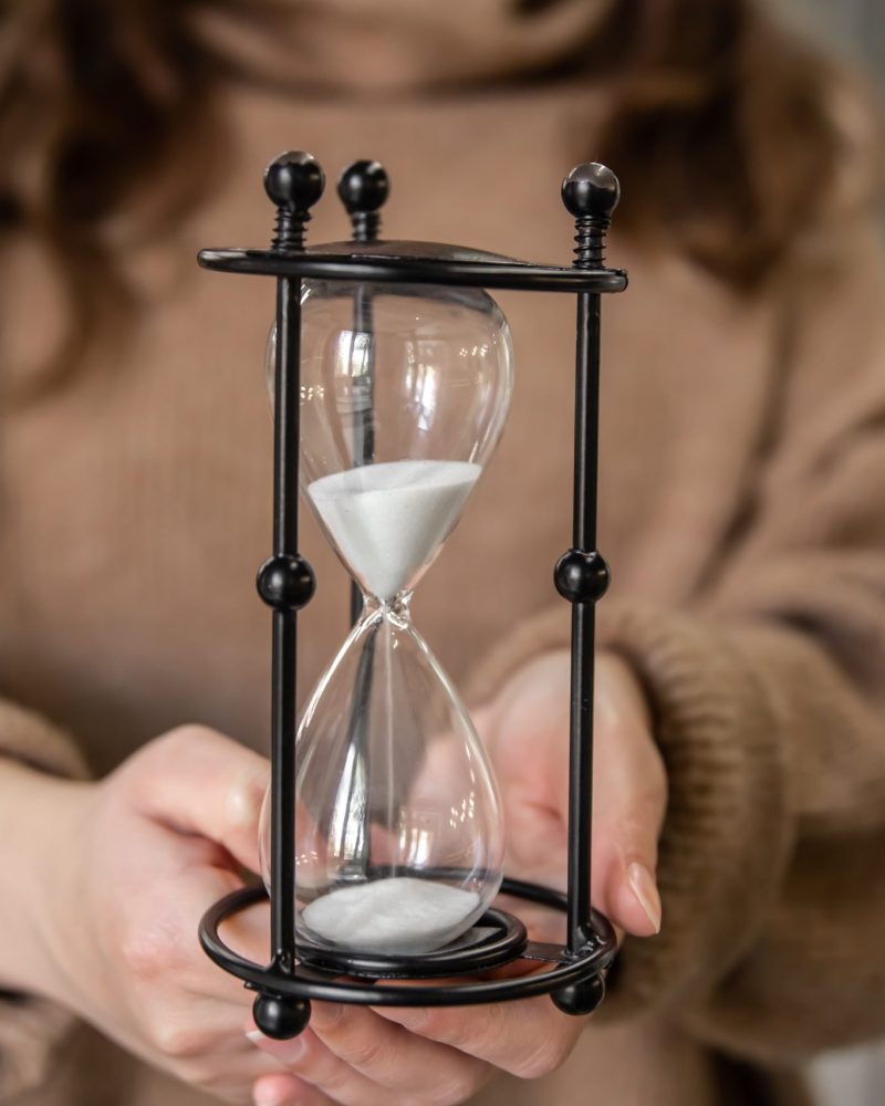 Vintage hourglass on blurred background of woman, time management concept.